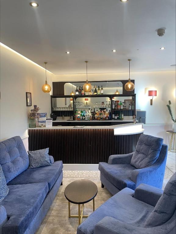 ein Wohnzimmer mit zwei blauen Sofas und einer Bar in der Unterkunft Canterbury Cathedral Lodge in Canterbury