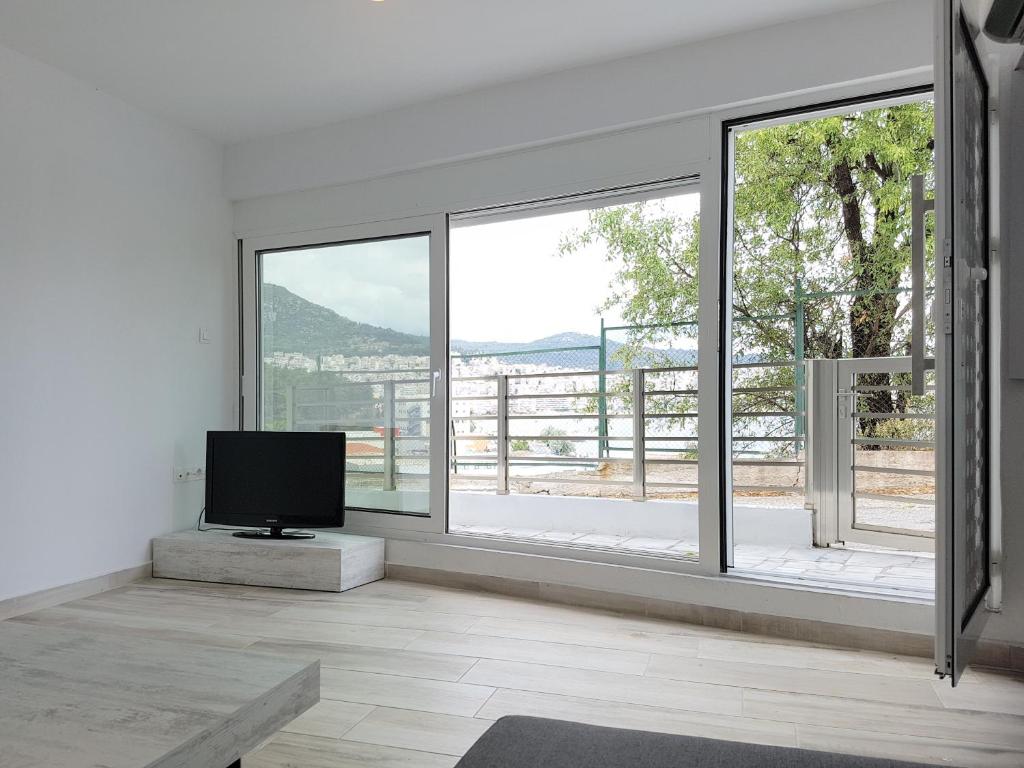 a living room with a tv and large windows at Panorama House* in Kavala