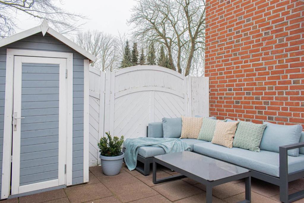 a patio with a blue couch and a white fence at Ferienwohnung Urlaubsflair in Timmendorfer Strand