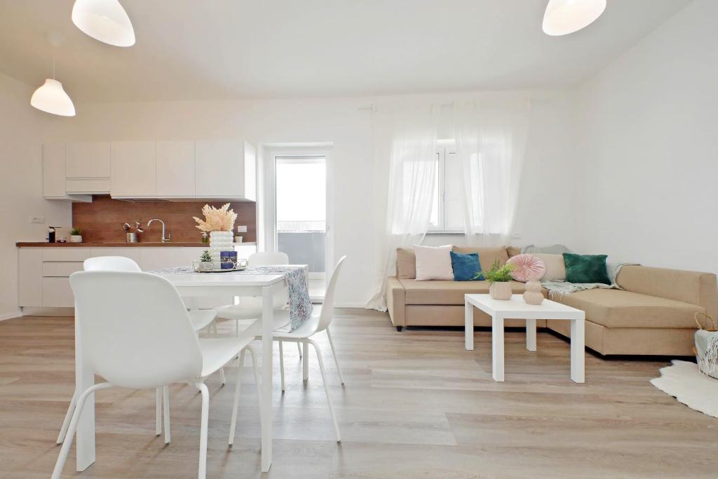 a white kitchen and living room with a table and chairs at Chic Suite - Aeroporto, self checkin e Free WiFi in Fiumicino