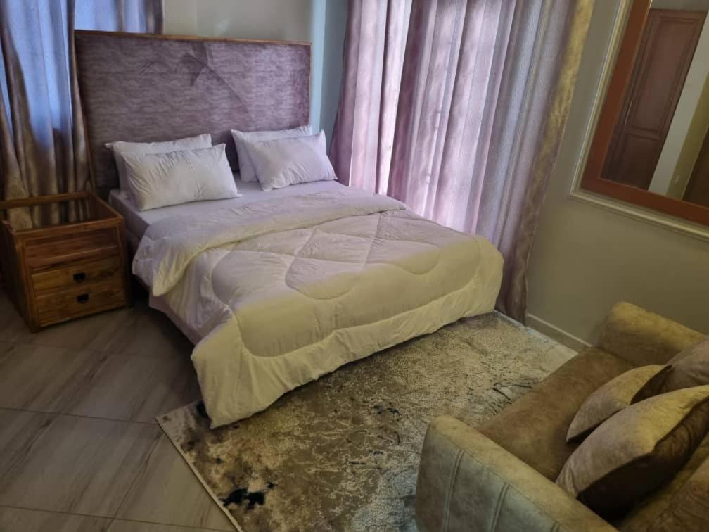達累斯薩拉姆的住宿－Elegant Mine Apartment -1，一间卧室配有一张大床和一把椅子