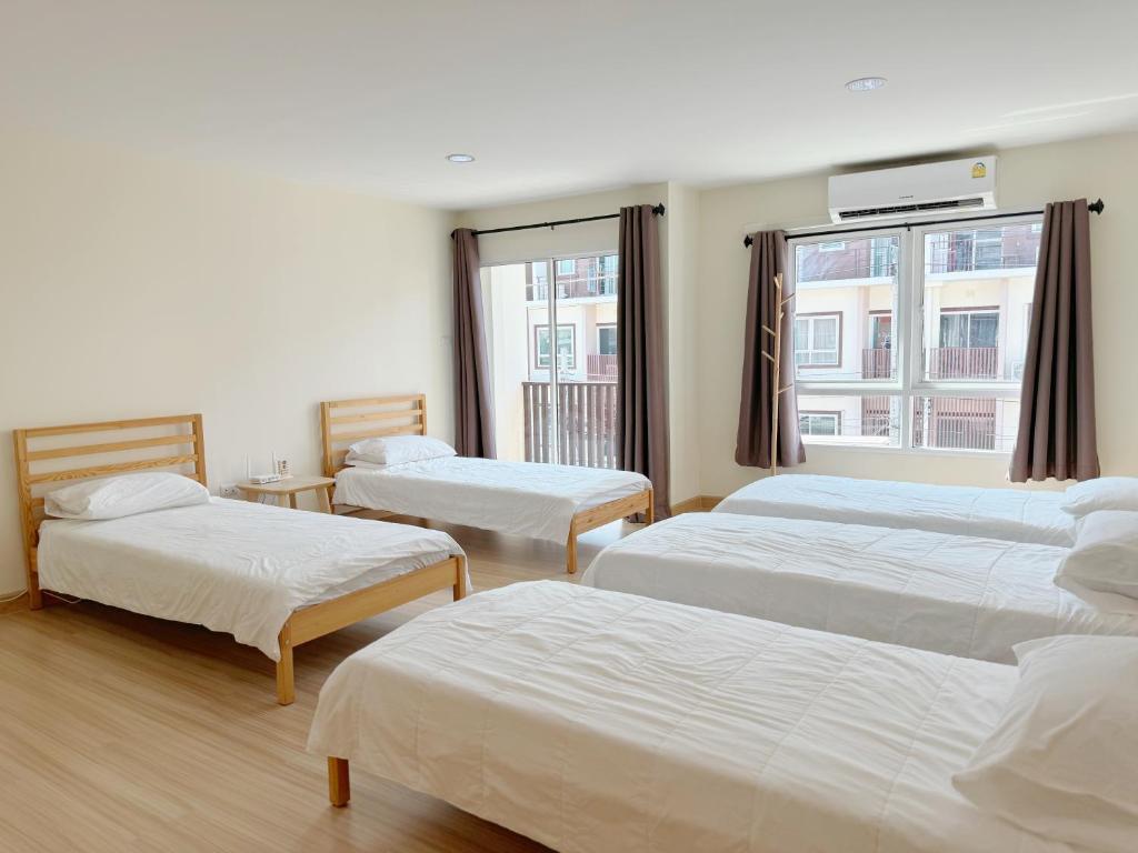 a hotel room with three beds and a window at Jira Private cozy room near Suvarnabhumi Airport in Lat Krabang