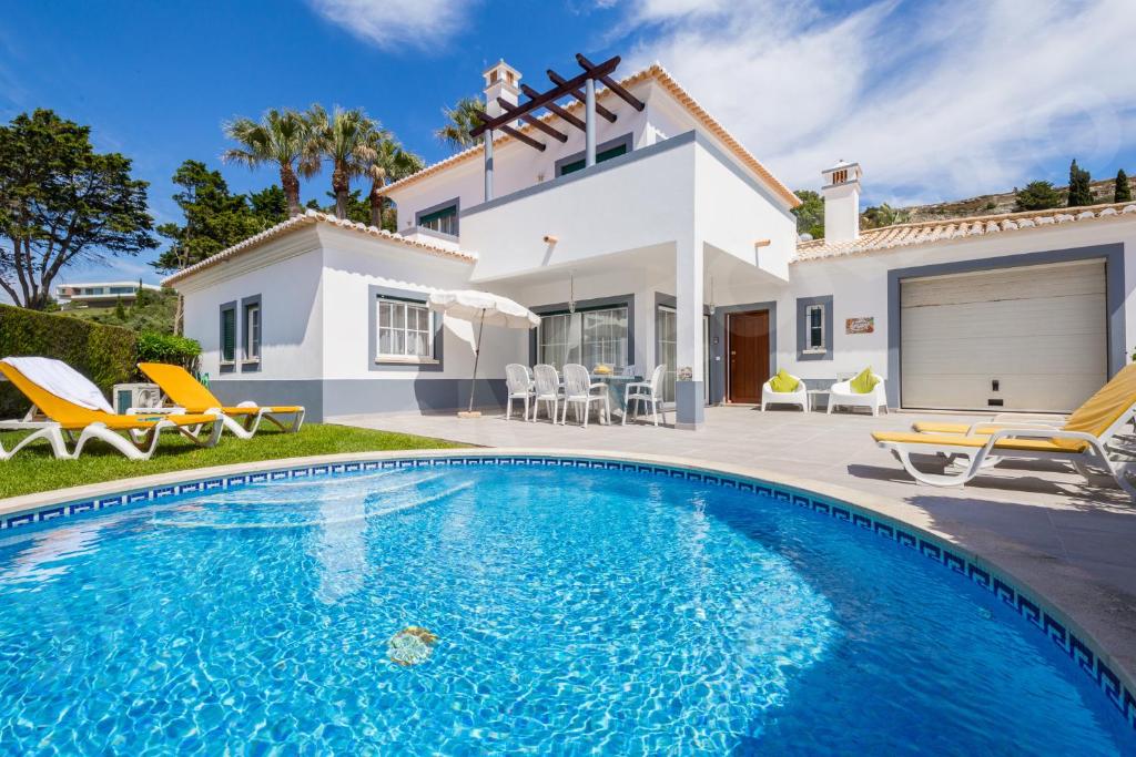 a villa with a swimming pool in front of a house at Jardim Secreto in Luz