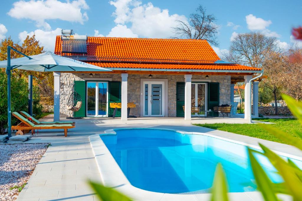 een huis met een zwembad en een oranje dak bij Villa Bajadera in Puljane