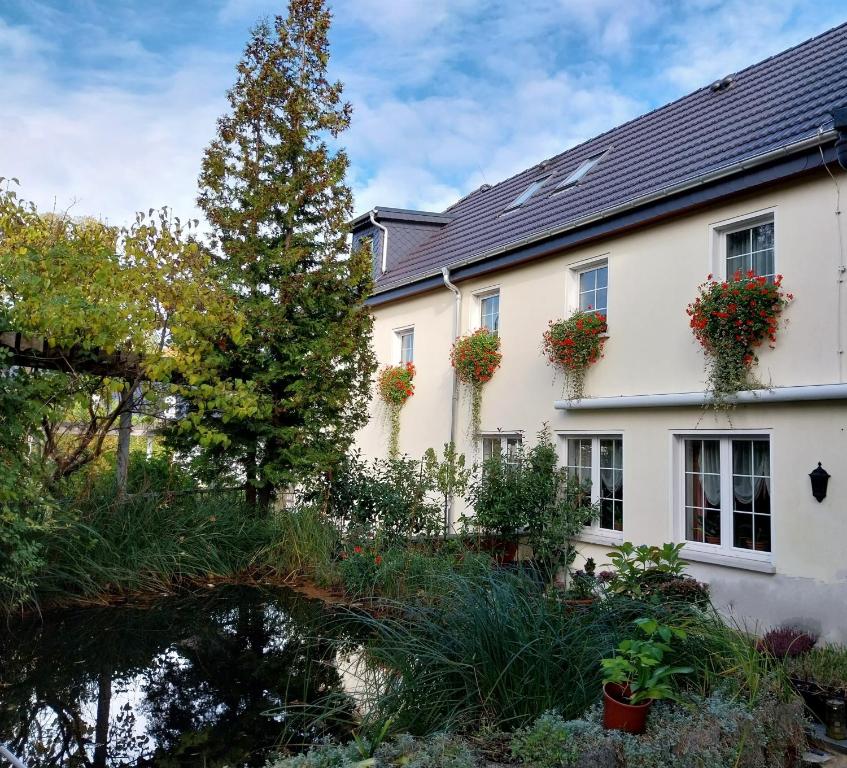 een huis met bloemen op de ramen en een vijver bij Ferienwohnung - Landhotel Waldschlößchen in Sohland