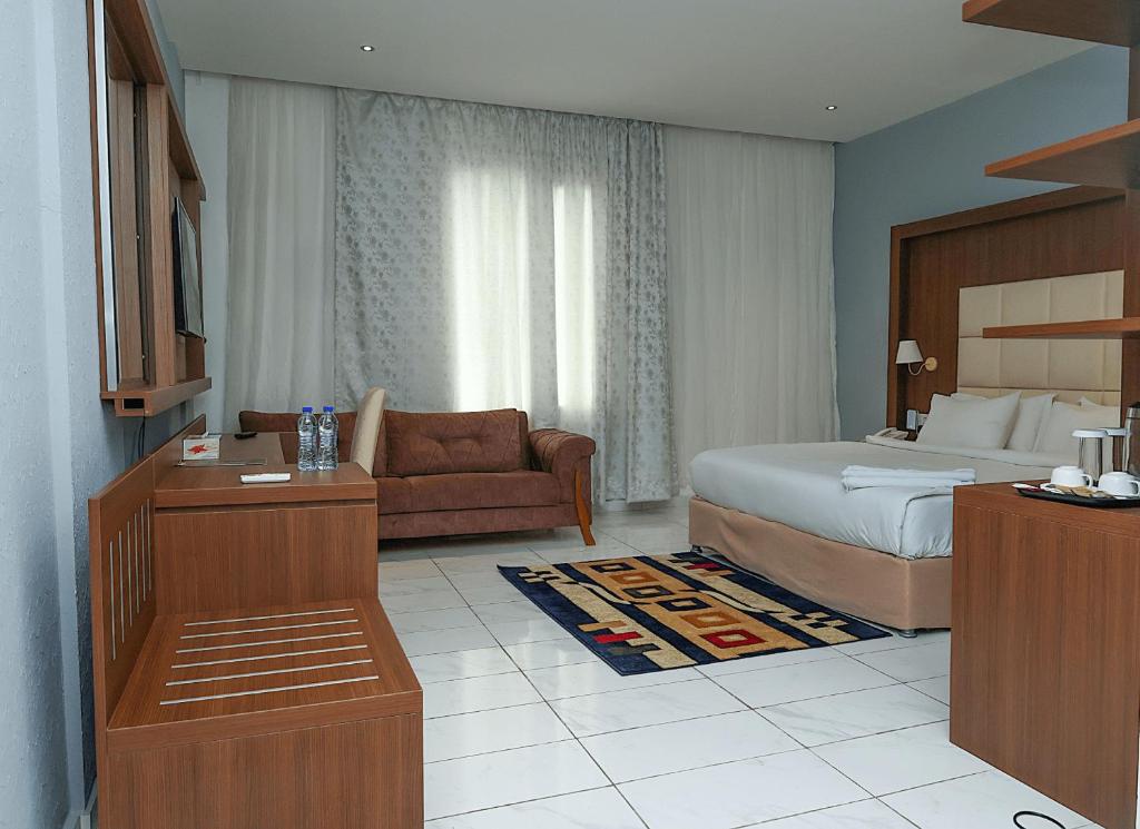 San Marino Hotel في آكرا: غرفه فندقيه بسرير واريكه