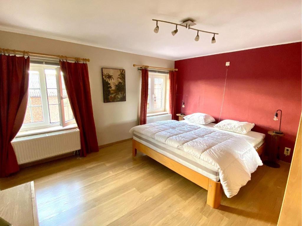Gîte Sur puremont في Burdinne: غرفة نوم بسرير بجدار احمر
