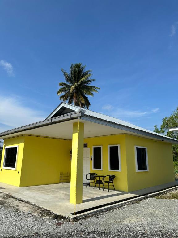 een geel huis met een palmboom erachter bij NoWa Residence in Mersing