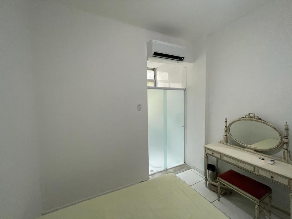 um quarto branco com um espelho e um lavatório em 3 quartos Copacabana no Rio de Janeiro
