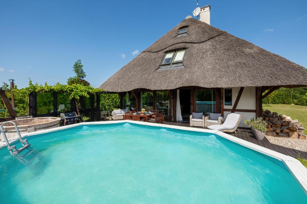 a thatched roof house with a swimming pool at mussurhouse in Ustka