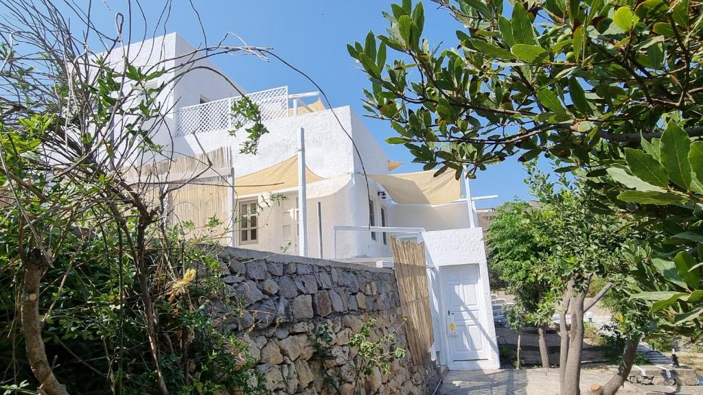 Casa blanca con pared de piedra en Eirini Residences, en Sapsila