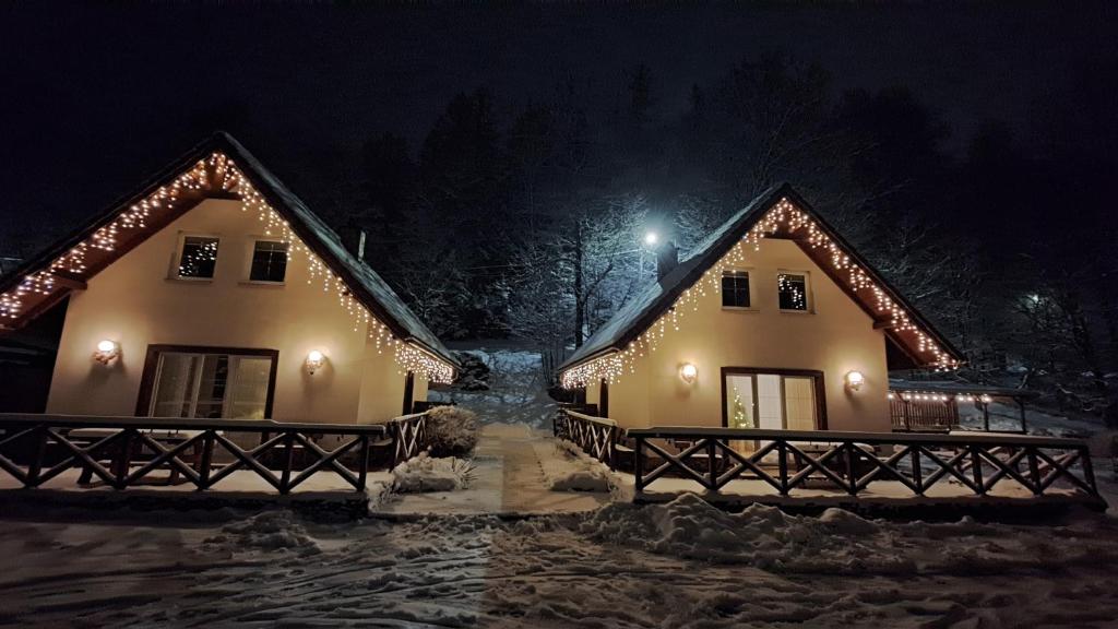 two houses with lights on them in the snow at night at Domki Pod Jesionami in Stronie Śląskie