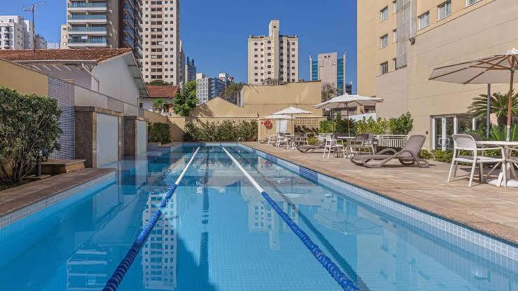 una gran piscina con sillas y sombrilla en M-Flat II Hotel - Vila Olimpia en São Paulo