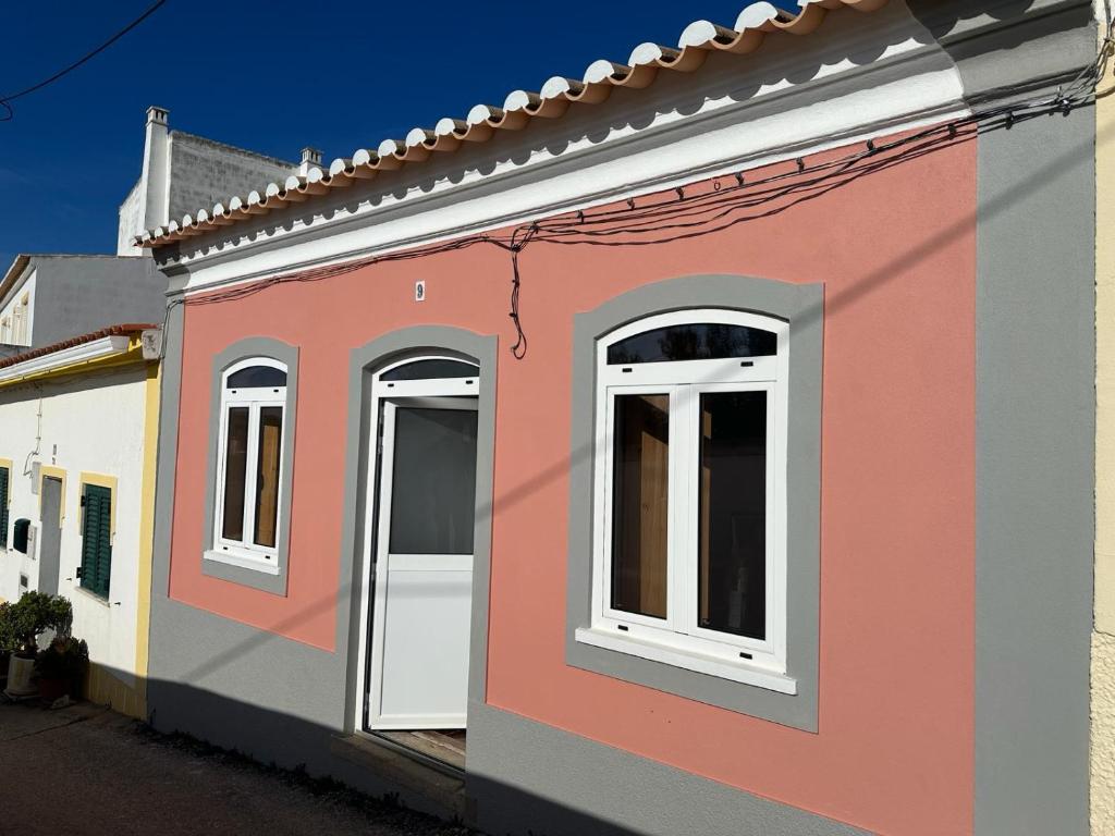 un edificio rosa con ventanas blancas en una calle en WavePortugal Surf & Stay, en Raposeira