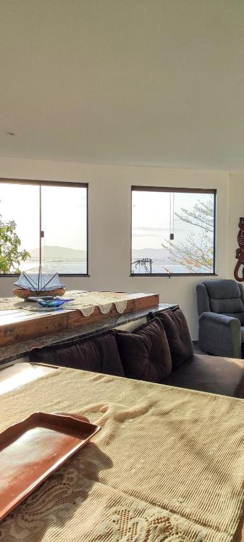 a living room with a couch and two windows at Apartamento pé na areia com vista para o Mar de Itaipu in Niterói