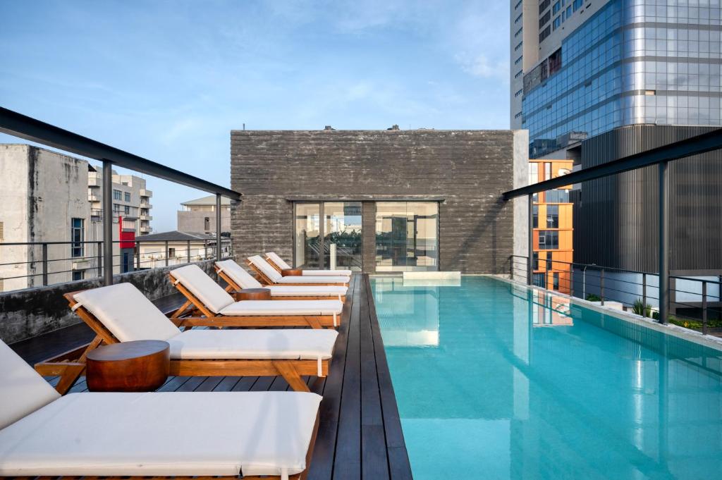 a swimming pool with lounge chairs on a building at Taprobane House in Colombo