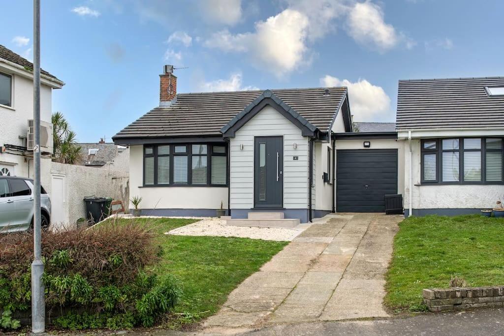 a white house with a black garage at Fully refurbished holiday cottage in Rhosneigr in Rhosneigr