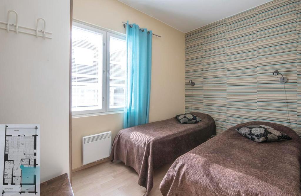 a room with two beds and a window with blue curtains at Levillenet Glacier Alpine Chalets at Levi Centre in Levi