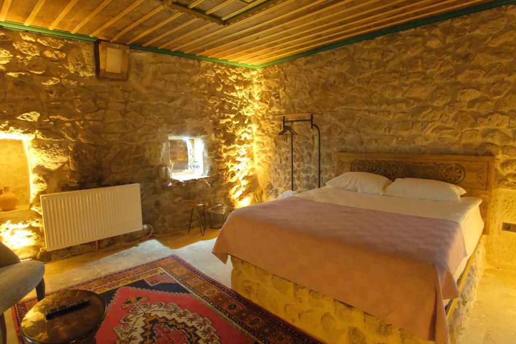 a bedroom with a bed in a stone wall at Euphoria Cave House in Nar
