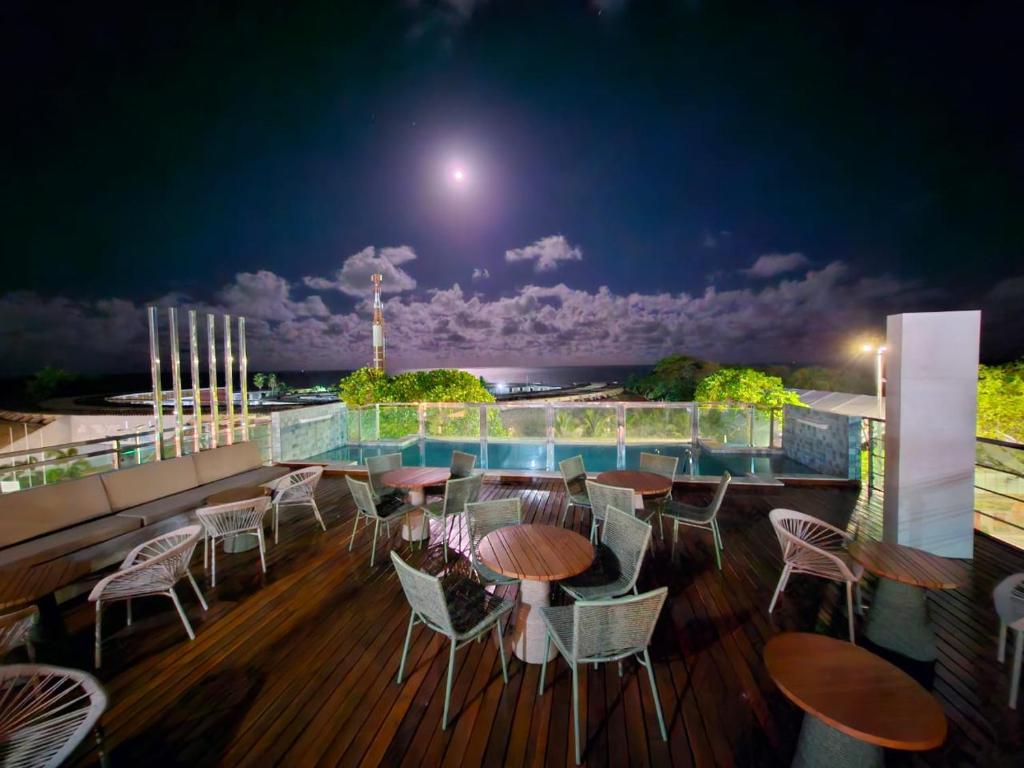 a balcony with tables and chairs at night at Israel Flat Tambaú in João Pessoa