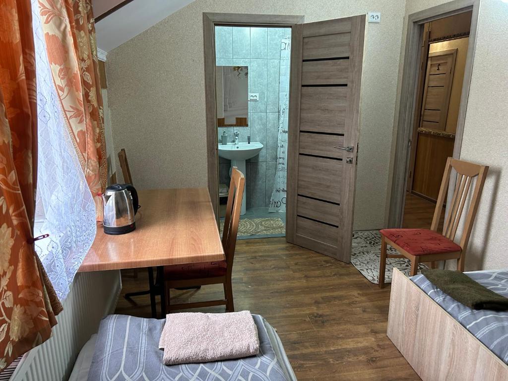 um pequeno quarto com uma mesa e uma casa de banho em Готель Максим em Drogovyzhe