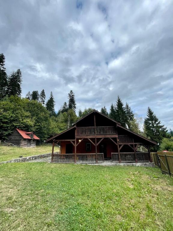 un granero de madera grande con un campo de hierba delante en Casa Fenyves Vendégház, en Băile Tuşnad