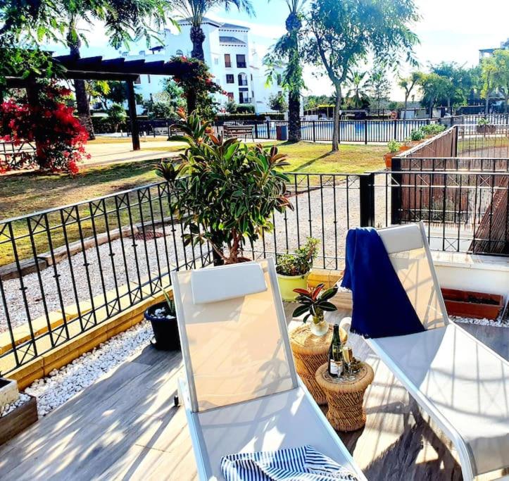 zwei Stühle und ein Tisch auf einer Terrasse mit Zaun in der Unterkunft Bajo Ortosa Valle Golf Resort in Murcia