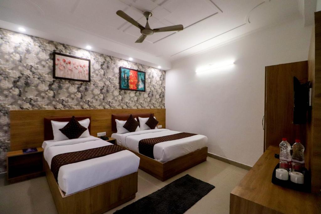 a hotel room with two beds and a ceiling fan at Hotel Ink Haven Near Delhi Airport in New Delhi