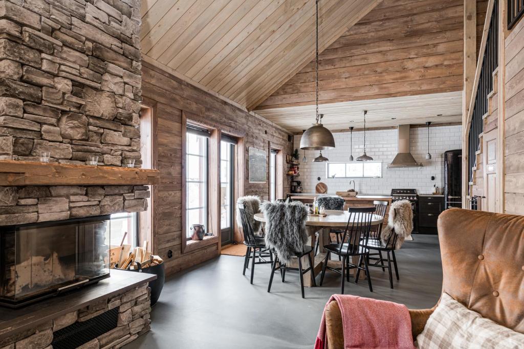 a dining room and living room with a stone wall at Luxurious cottage with sauna overlooking mountains in Vemdalsskalet