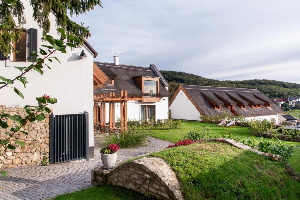a house with a stone wall and a yard at Pipitér Rooms & More in Szigliget