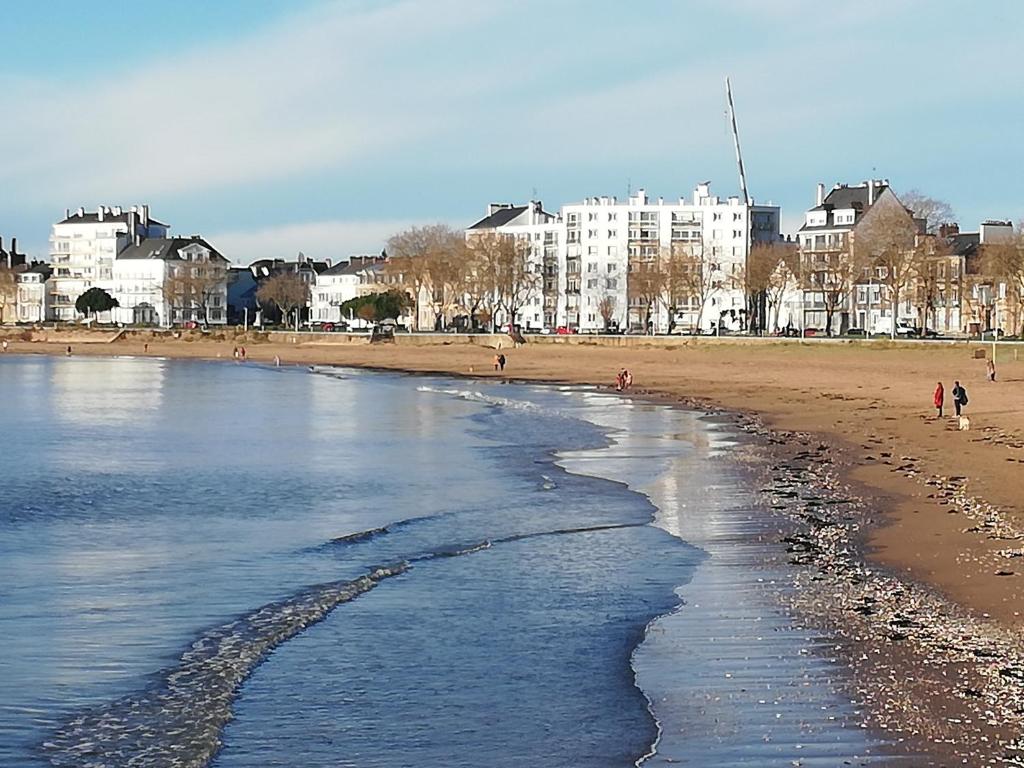 une plage avec des gens qui marchent sur le sable et des bâtiments dans l'établissement Appartement de 3 chambres face à la mer, à Saint-Nazaire