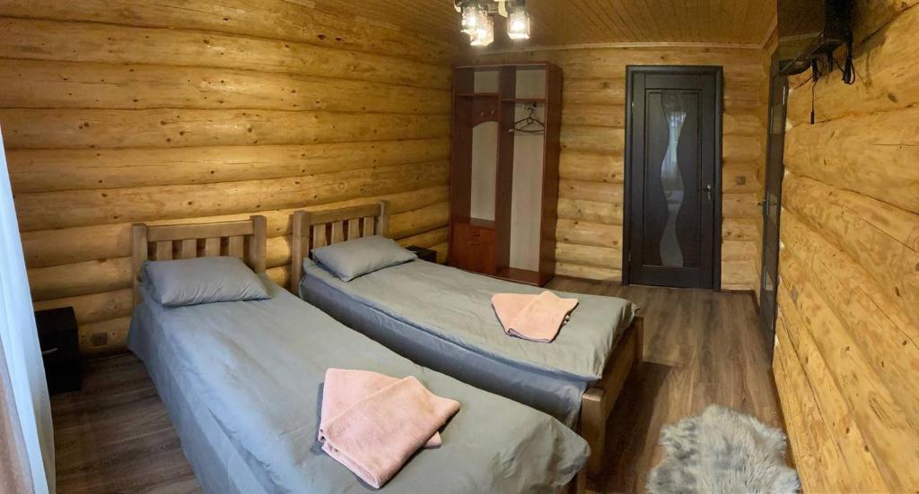 two beds in a room with wooden walls at Садиба у Пасічника in Pilipets