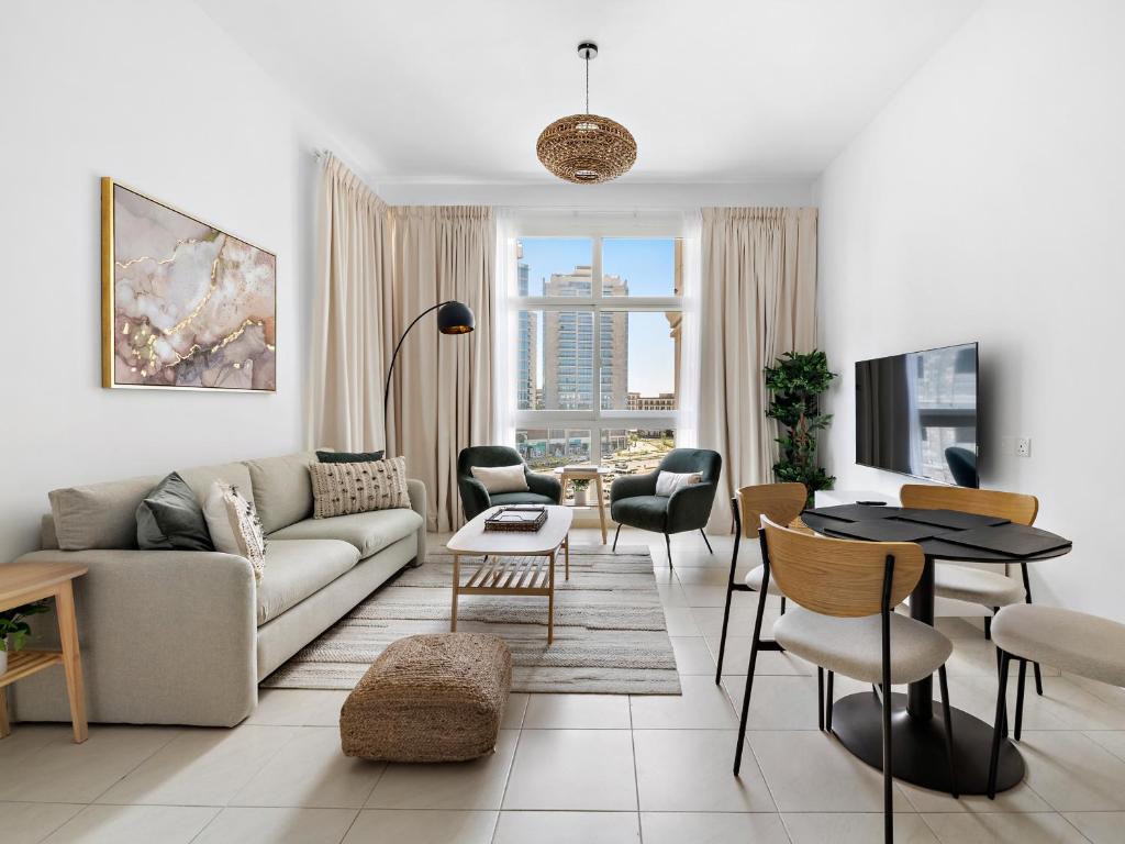 uma sala de estar com um sofá, uma mesa e cadeiras em Stunning and Brand New La Fontana 513 no Dubai