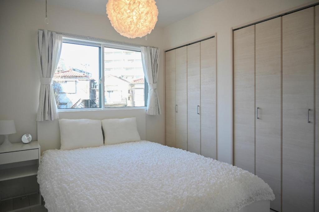 a bedroom with a bed and a window and a chandelier at YIAN-Kamiochiai house in Tokyo