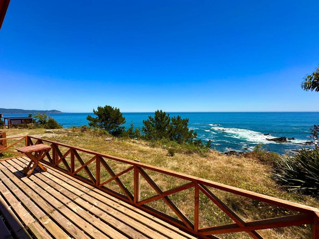 a wooden bench sitting on top of a hill overlooking the ocean at Cabañas Vista al Mar in Valdivia