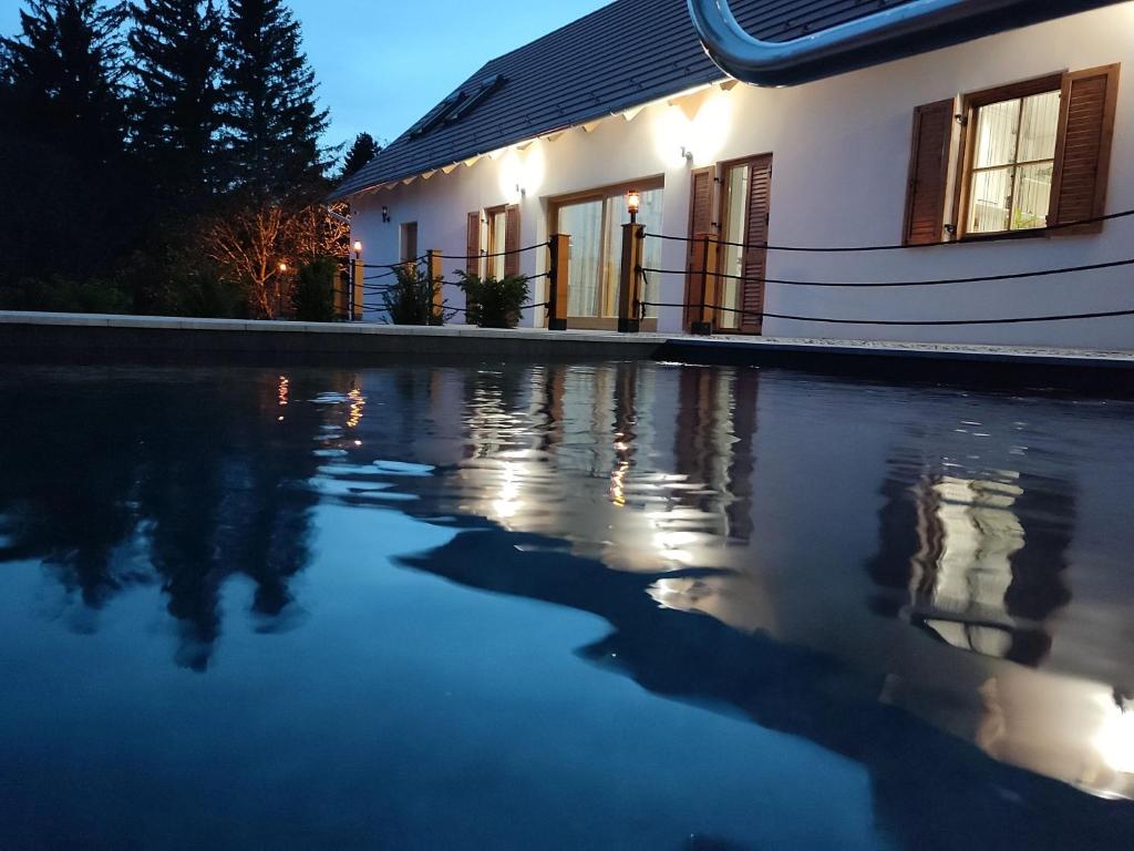 une maison avec une piscine d'eau en face de celle-ci dans l'établissement Vértes Gyöngye Vendégház Vérteskozma, 