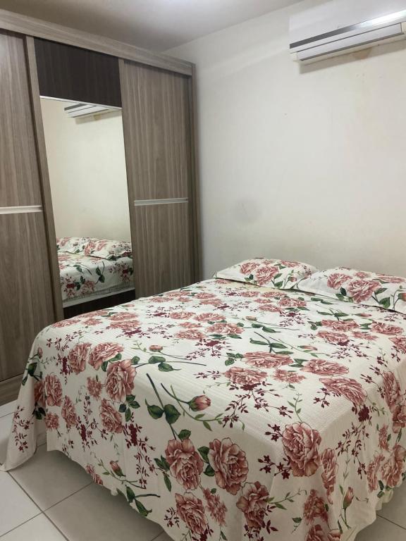 um quarto com uma cama com colcha floral em Apartamento bossa nova em Aracaju