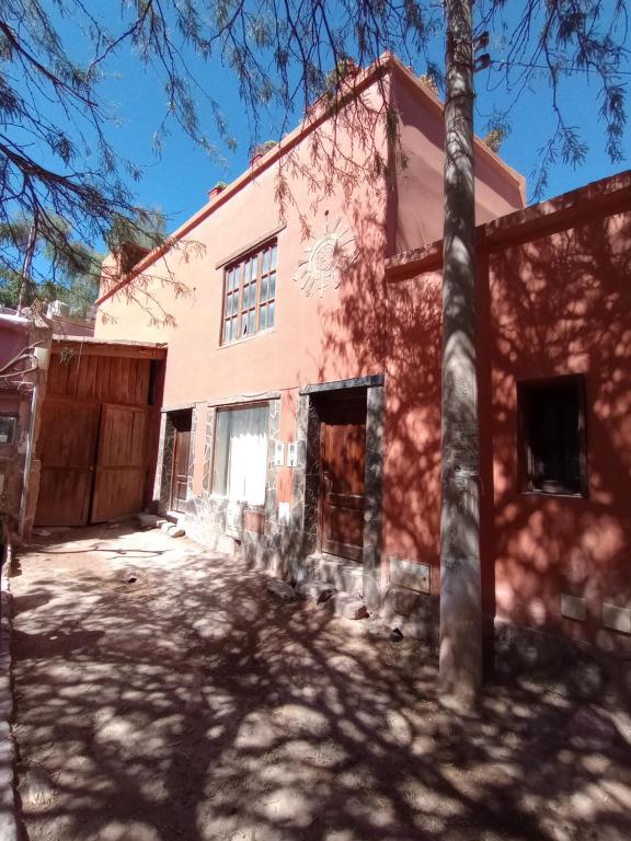 czerwony dom z drzewem przed nim w obiekcie Los Tatas ,departamento w mieście Purmamarca