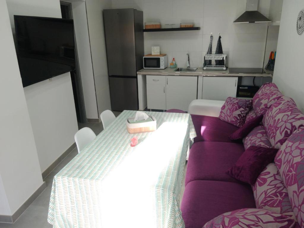 sala de estar con sofá púrpura y mesa en Apartamentos los carros 2, en Guadix