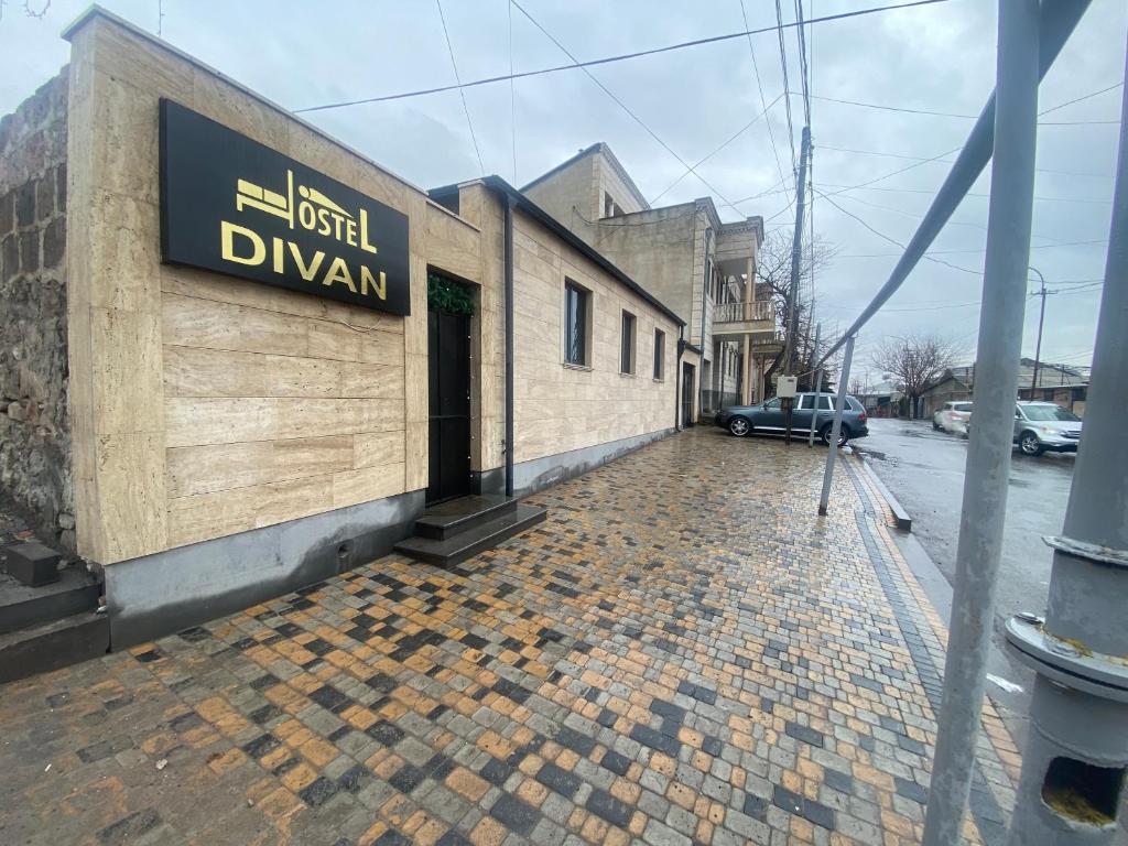 un edificio con un letrero al lado de una calle en Hostel Divan, en Ereván