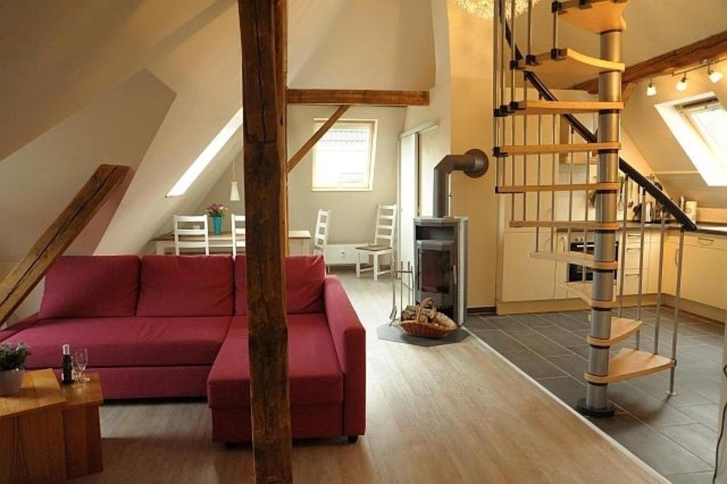 sala de estar con sofá rojo y escalera de caracol en Ferienwohnung Müller-Wulf, en Schleswig