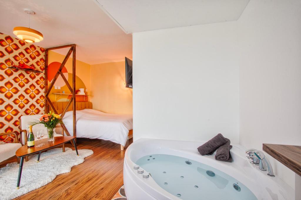 a bathroom with a tub and a bedroom at Suite année 70 - Jacuzzi et Balcon in Caen