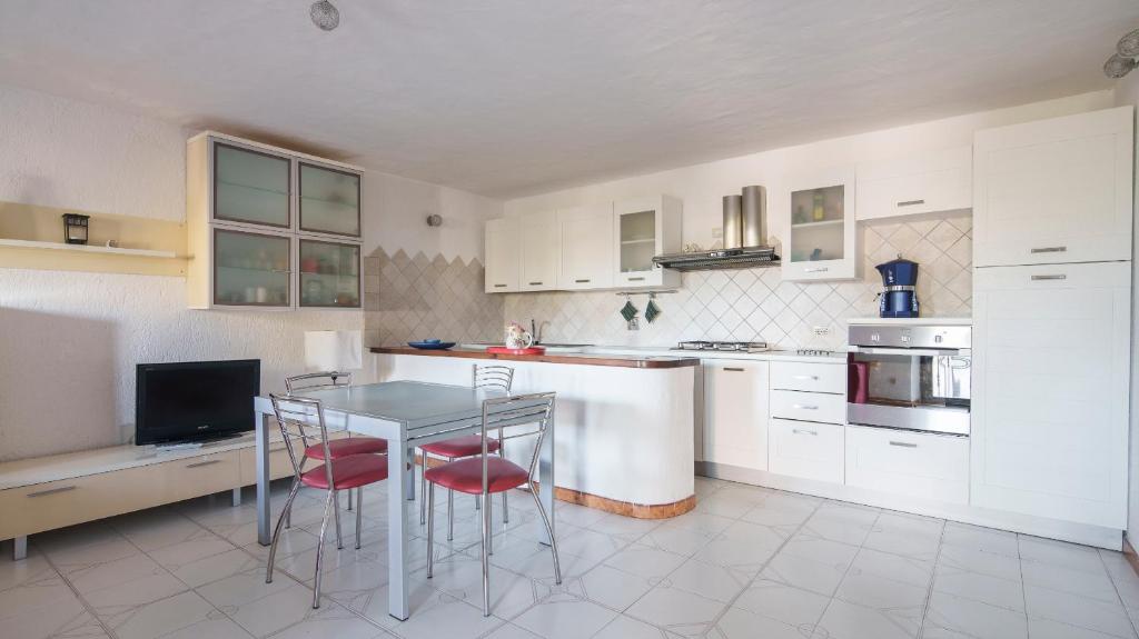 - une cuisine avec des placards blancs, une table et des chaises dans l'établissement Welcomely - Acqua e Tramonto, à Olbia