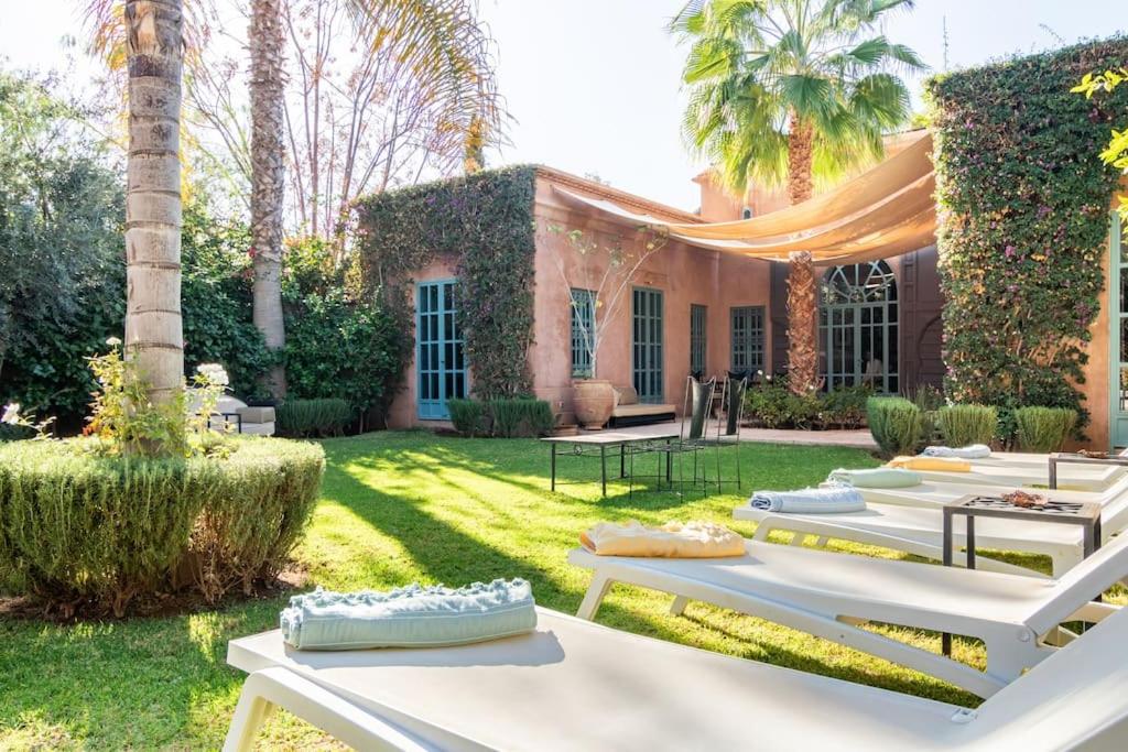 a row of chaise lounges in front of a house at Villa Pauline with private pool & garden, hotel service and no insight. in Marrakech