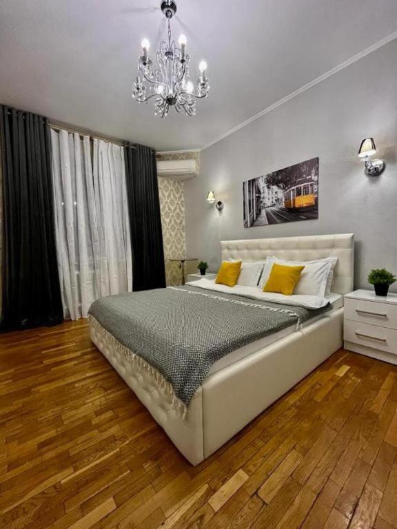 Un dormitorio con una cama grande y una lámpara de araña. en Апартаменты MOON APARTMENTS - ZENKOVA 86, en Almaty