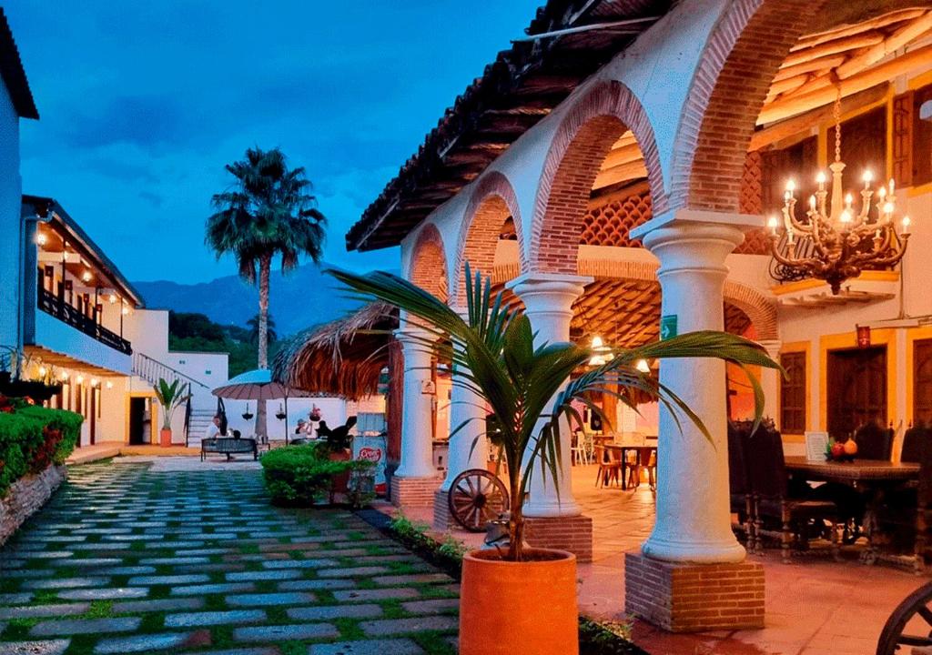 a building with a palm tree in a courtyard at Hotel Santa Barbara Colonial - Santa Fe de Antioquia in Santa Fe de Antioquia