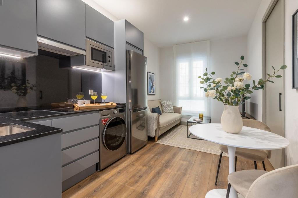 een keuken en een woonkamer met een koelkast en een tafel bij 2 single beds in Chamberi Quevedo III in Madrid