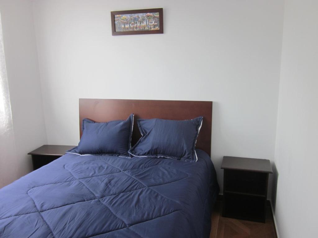 a bed with a blue comforter in a bedroom at Apartamento terrazas de cajica in Cajicá