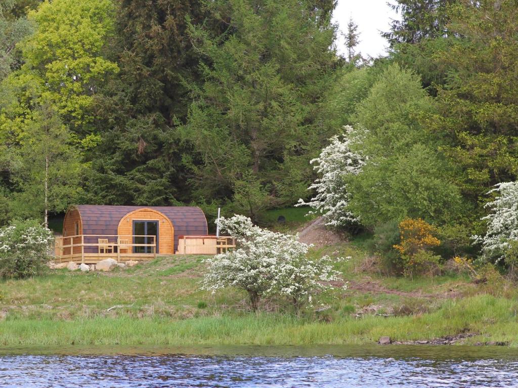 a wooden cabin on the side of a river at Kendoon Cabin in Carsphairn