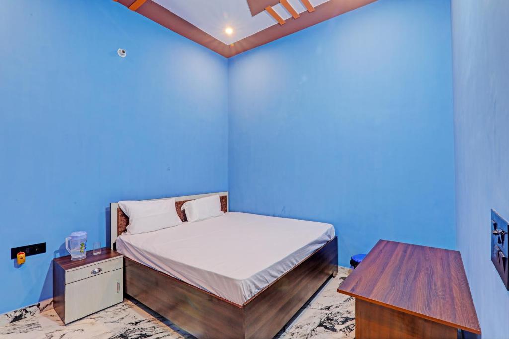 a blue room with a bed and a table at OYO Green Valley Guest House in Sultānpur